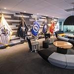 Full Sail军校学生成功中心的一张图片显示了一张大沙发, small meeting rooms, 以及代表美国各军种的旗帜.